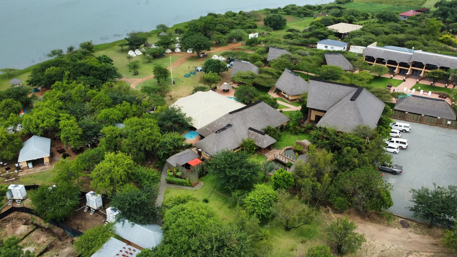 Lodge buildings among trees beside water, seen from above
